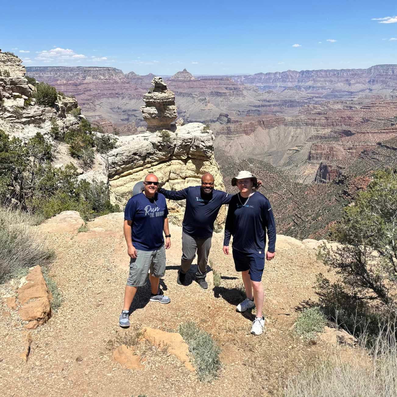Three Scimitar team members posing together on a trail overlooking the Grand Canyon.