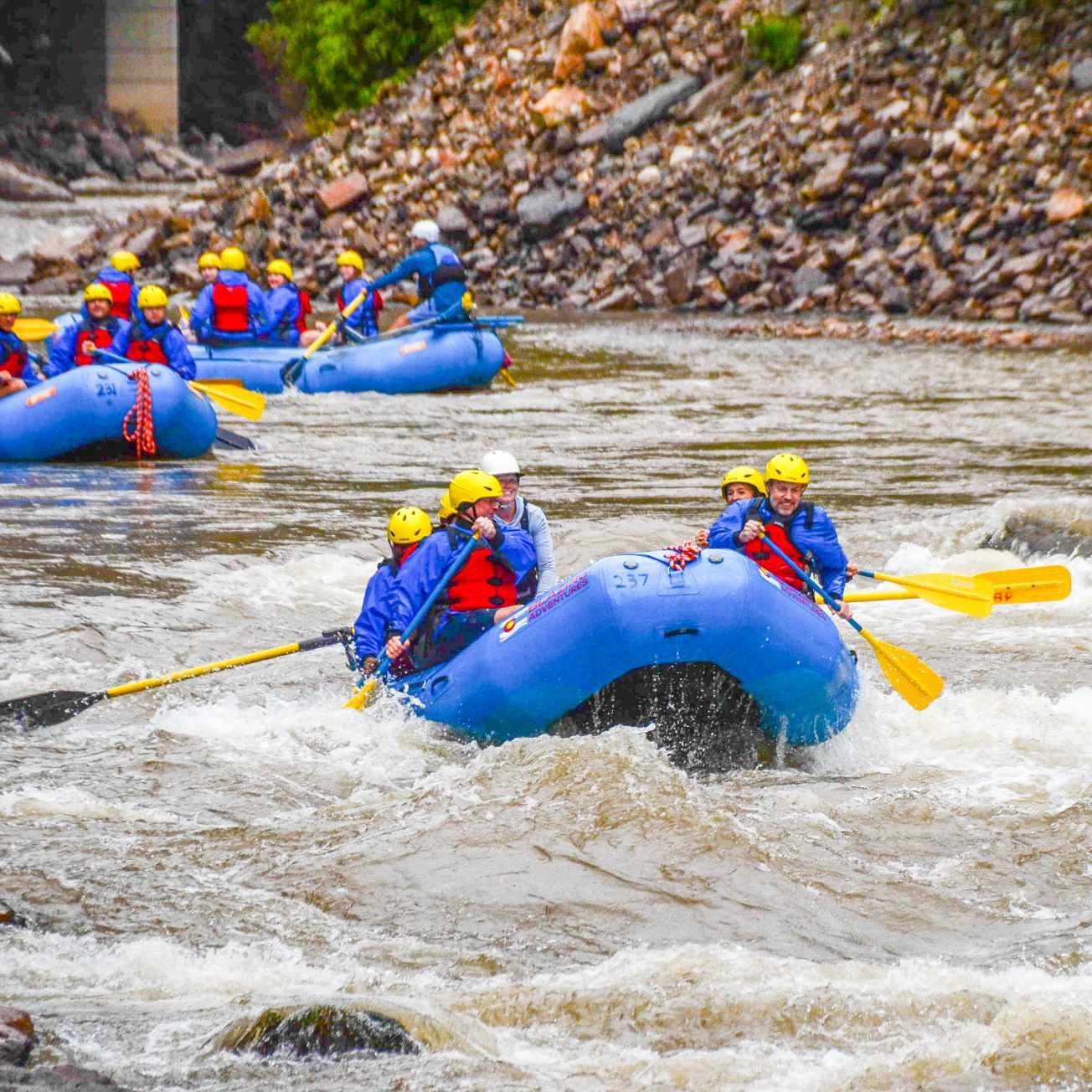 Scimitar team members whitewater rafting together through river rapids.